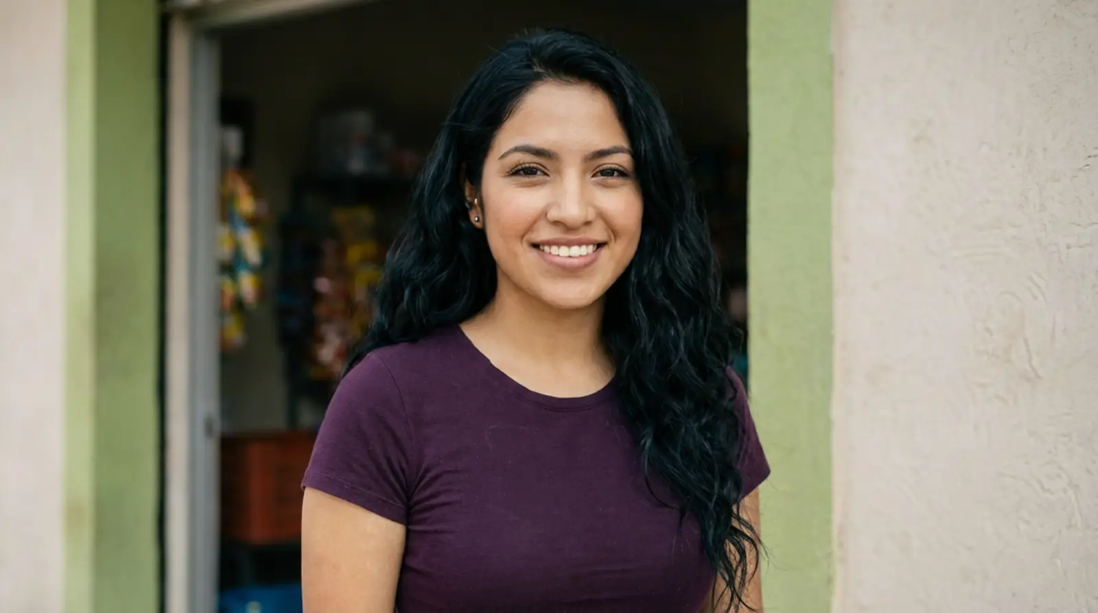 Mujer joven sonriente frente a su pequeño negocio